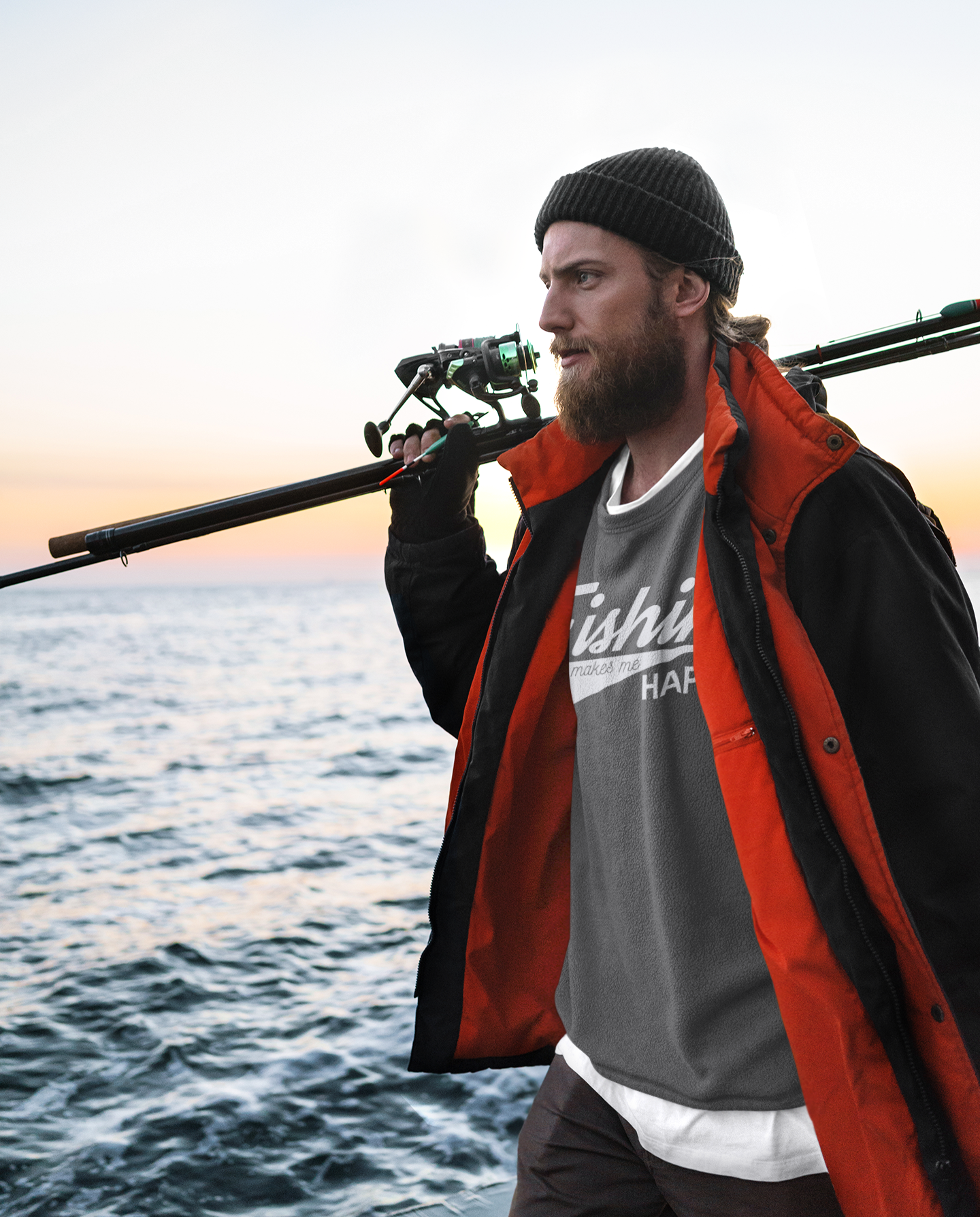 A man holding a fishing pole over his shoulder standing by the ocean.